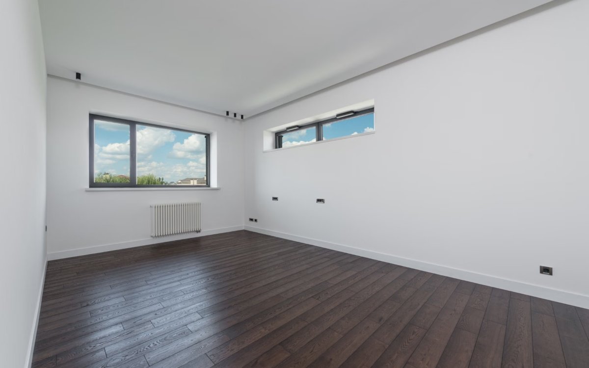An empty room with white walls and daylight raking across them from the window